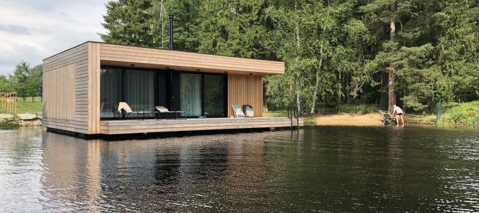 Moderní plovoucí dům na rybníku obklopeném lesy