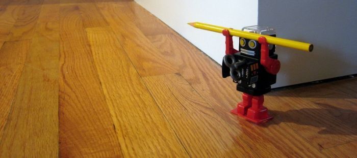 Malý robot stojí na podlaze z palubek